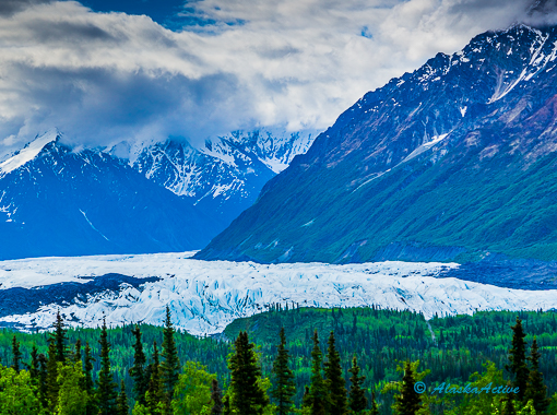 Kayakers paddling near a massive blue tidewater glacier in Kenai Fjords